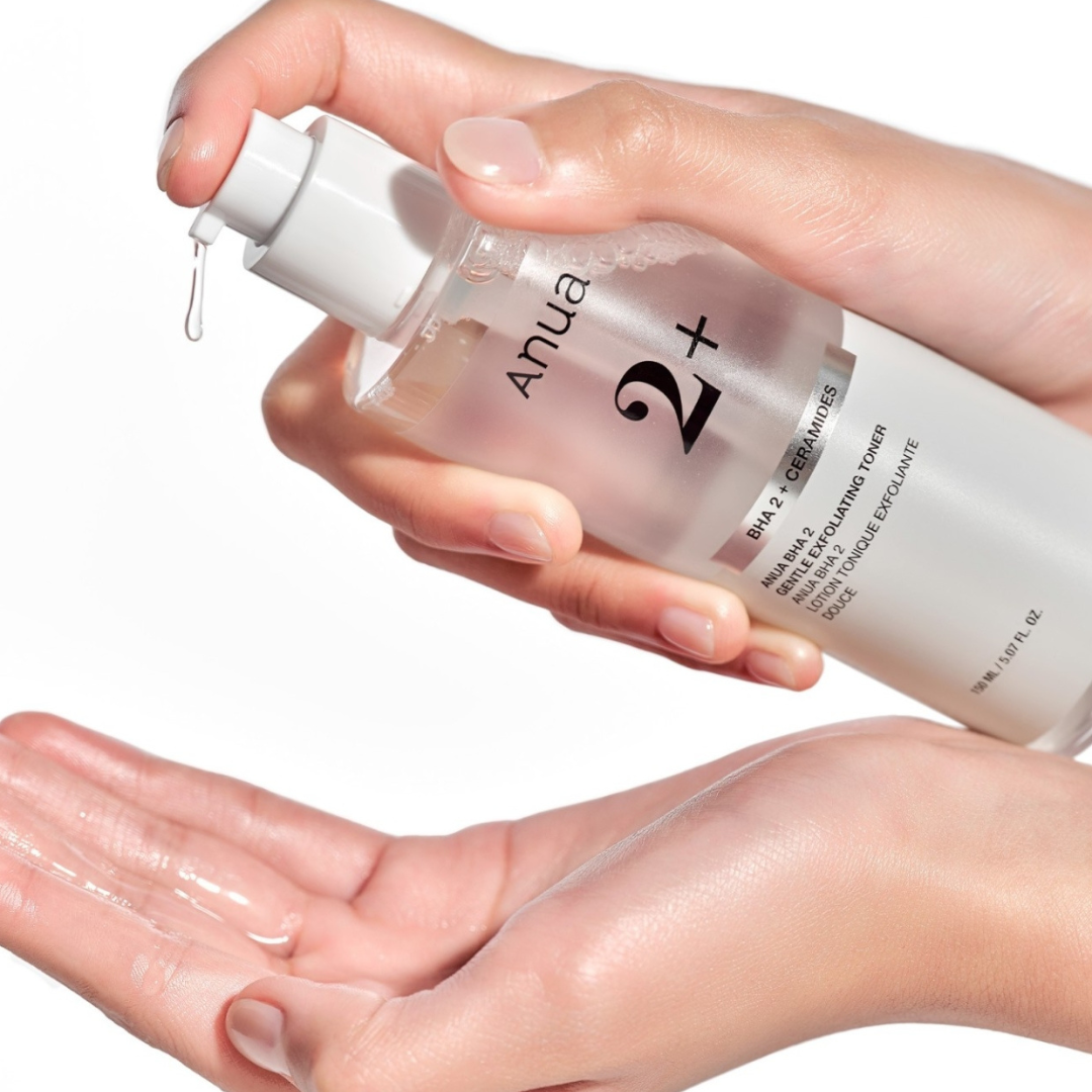 Hand holding a bottle of '2+' skincare product with a white background