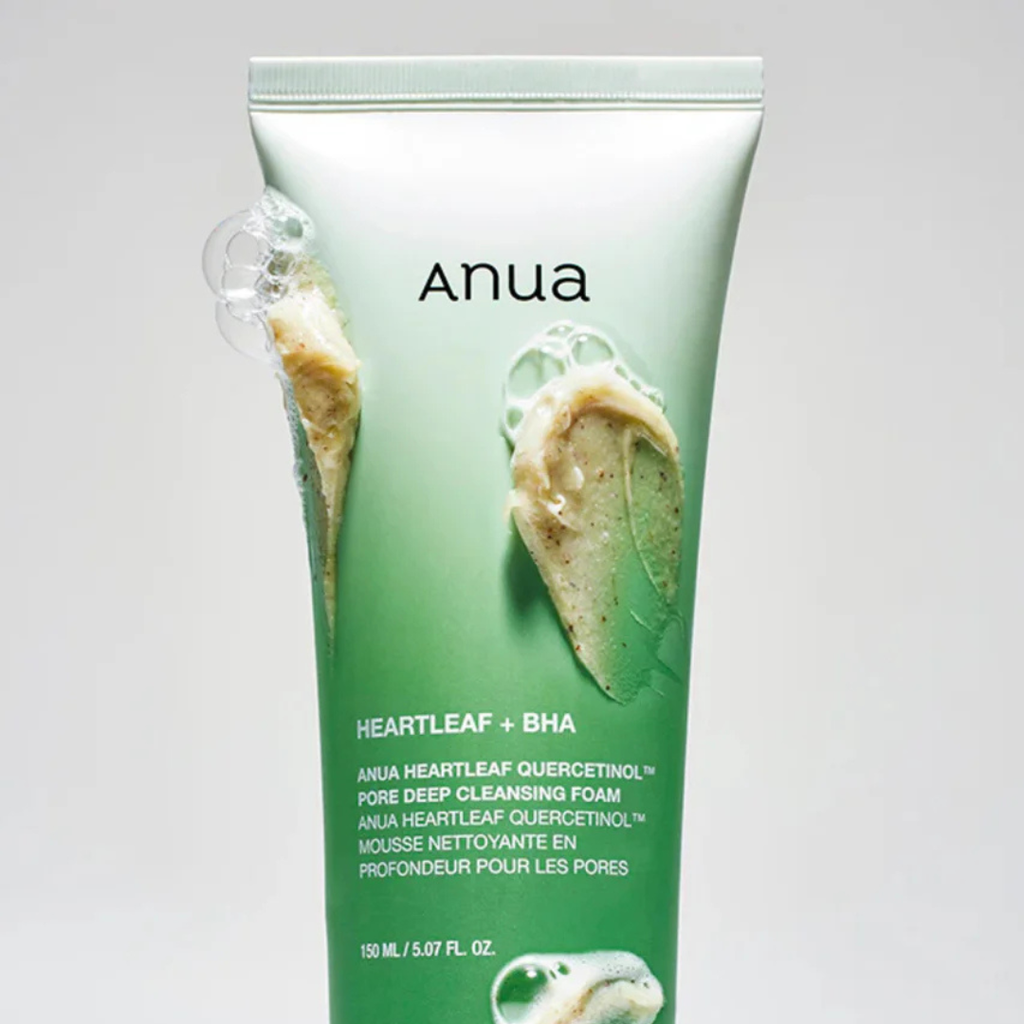 Green skincare product tube labeled 'Anua' on a light gray background