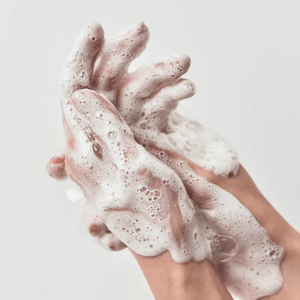 Foamy hands with soap suds on a plain background