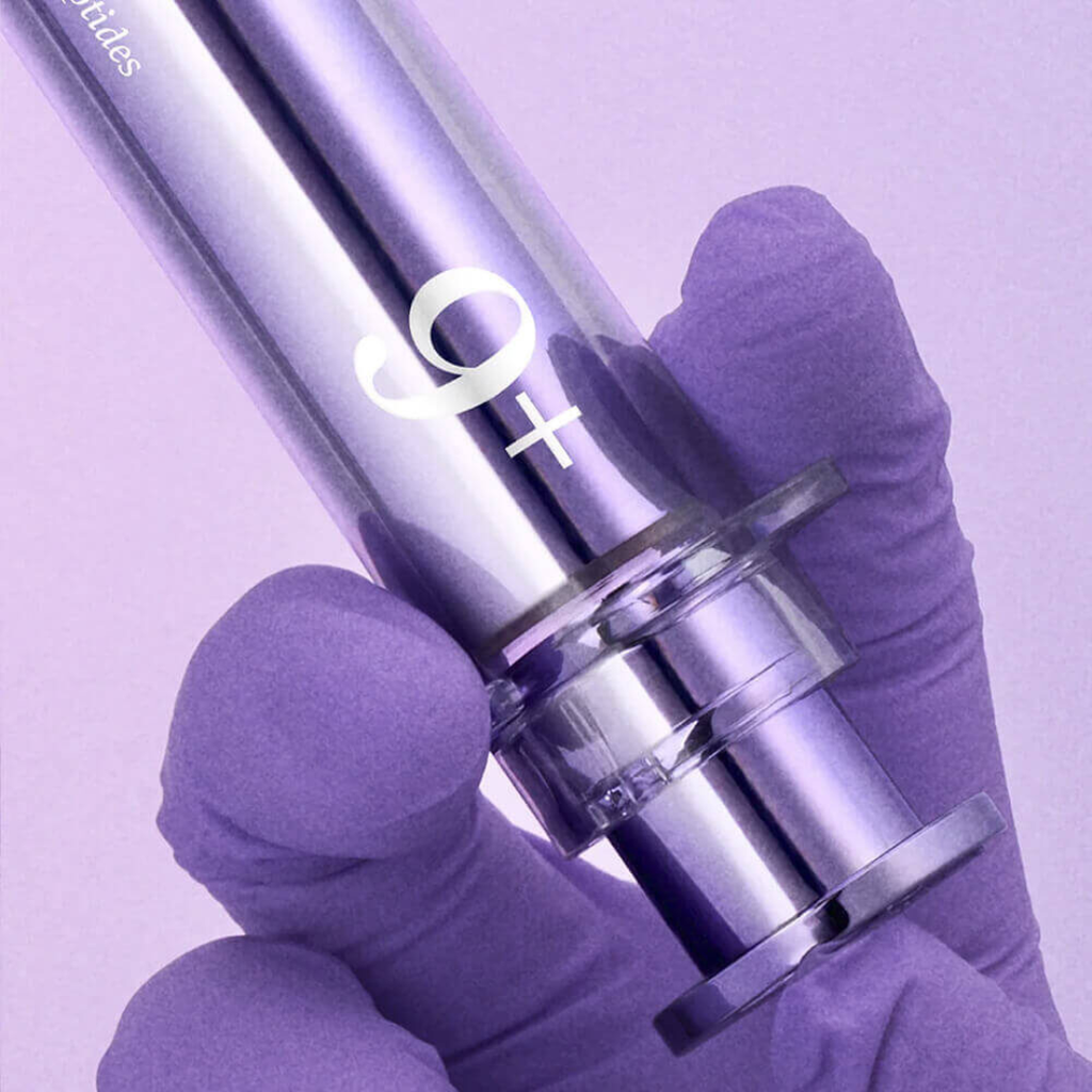Purple syringe held by a gloved hand against a purple background