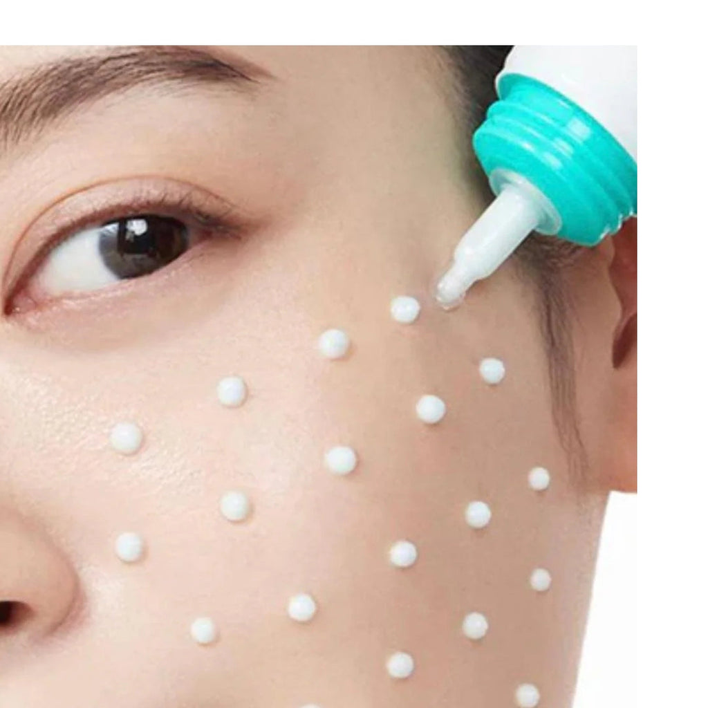 Person using a white tool with a green nozzle on their face, applying small white beads.